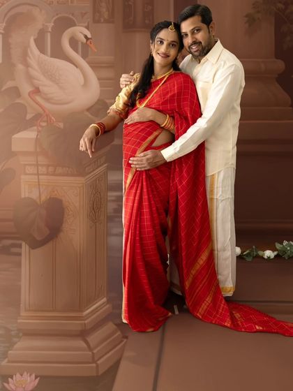 A graceful couple's portrait in red and white traditional wear, set against a painted backdrop featuring a swan, symbolizing purity and grace.