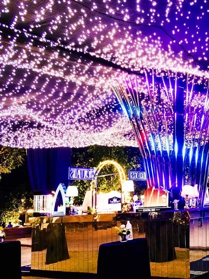 An outdoor cocktail night under a sky of fairy lights. The central art installation and mirrored tables create a modern, electric vibe at Alila Fort Bishangarh.