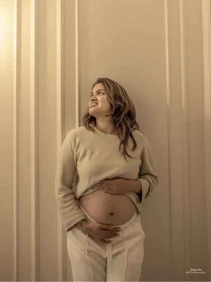 A beautifully lit solo portrait against a paneled wall. The warm tones and her hopeful upward gaze create a photo filled with warmth and anticipation.
