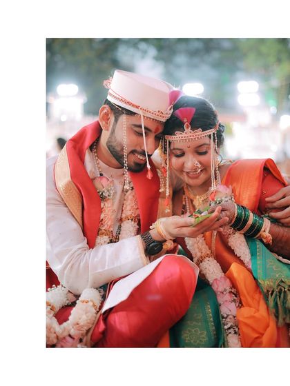 A close-up of a beautiful ritual. The couple holds 'paan' leaves in their hands, a significant part of the Maharashtrian wedding ceremony, captured with warmth and detail.