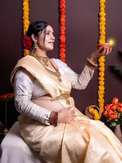 A beautiful and traditional maternity portrait celebrating cultural heritage. The mom-to-be is dressed in an elegant saree, holding a diya, creating a warm and classic image.