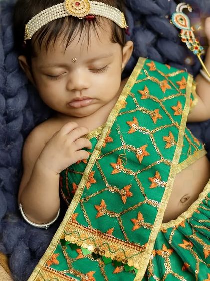 A detailed close-up of baby Radha, capturing the peacefulness of her sleep and the beautiful textures of her outfit.