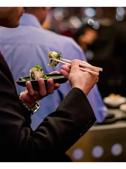 A guest enjoys a piece of our freshly made sushi. Our canapés are designed to be elegant and easy to eat while standing, allowing guests to socialize without interruption.