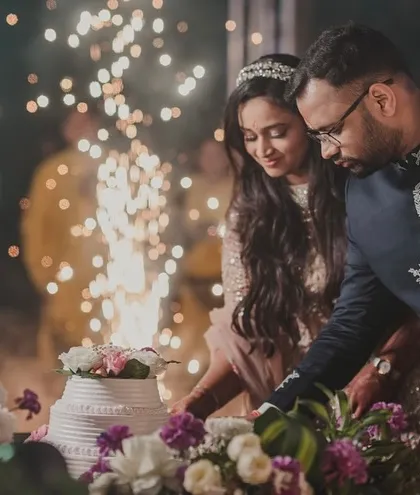 Even the cake cutting can be a spectacle. A simple sparkler adds a touch of magic to this sweet moment, with the floral-adorned cake table completing the scene.
