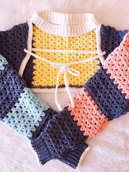 A flat-lay of the Gaea Shrug, showcasing the unique construction and color-blocking.