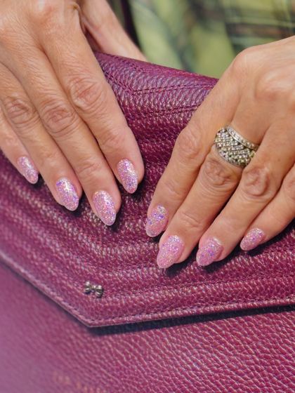 A close-up of these dazzling pink glitter nails. The light catches the multi-tonal glitter, creating a beautiful shimmering effect that is both fun and elegant. This is a great option for the festive season.