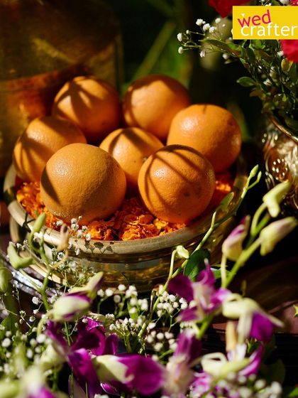 A close-up of fresh oranges arranged in a silver bowl, a unique and colorful element used in the fusion Haldi decor.