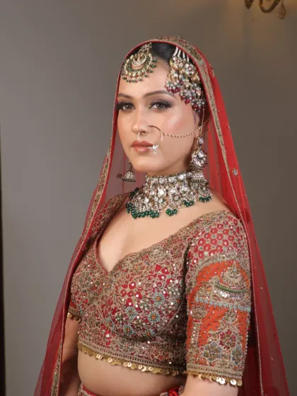 A portrait of a bride in her red lehenga, showing off her beautiful jewelry and the radiant makeup that makes her shine.