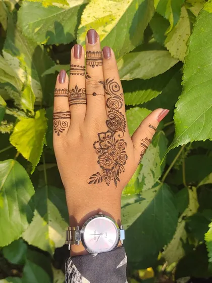 Sometimes, less is more. This is an example of a modern, minimalist henna design on the back of the hand, featuring a delicate floral vine and simple finger details.