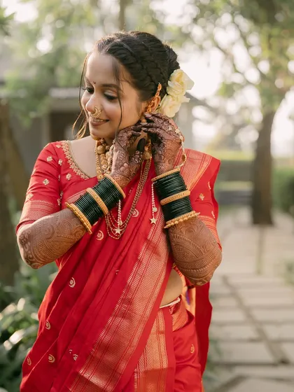 The bride adjusts her traditional earrings, her intricate henna on display.