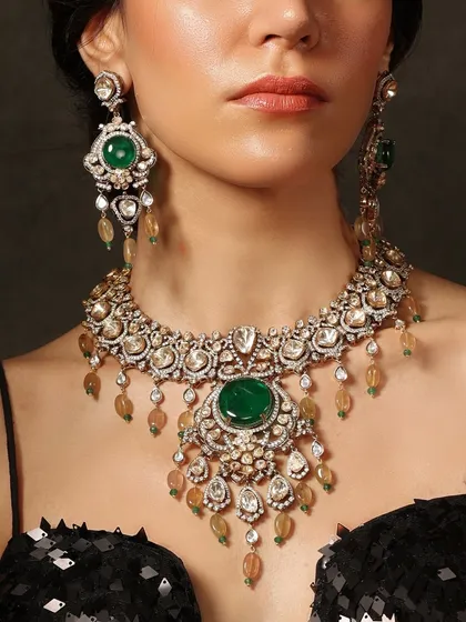The centerpiece of any bridal look. This grand Emrosia necklace features a large central emerald surrounded by intricate polki work and cascading drops.