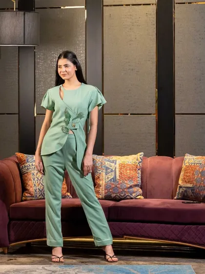 A standing pose of the same mint green outfit, providing a clear, full view of the top's unique cut and embroidery. This is an essential shot for any designer lookbook.