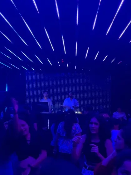 A full view of the dance floor under the cool blue lights, with everyone lost in the music.