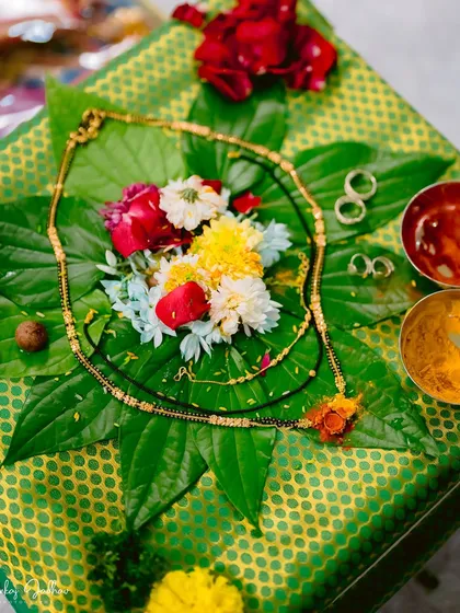 The sacred symbols of marriage: a mangalsutra and rings laid out on a betel leaf with flowers and turmeric, ready for the ceremony.