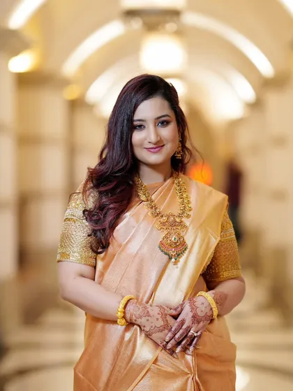A classic portrait of the bride, with a gentle smile and hands clasped. The focus is on her radiant face and the intricate details of her traditional jewelry.
