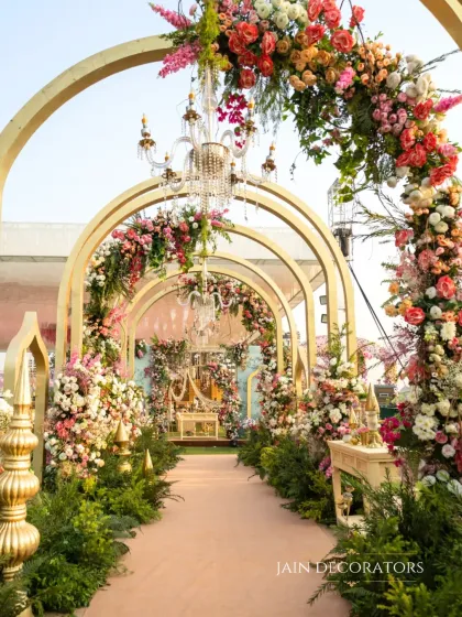 Another perspective of the enchanting floral archway, this time with chandeliers hanging within each arch. This detail adds a touch of classic elegance to the romantic, garden-like feel.
