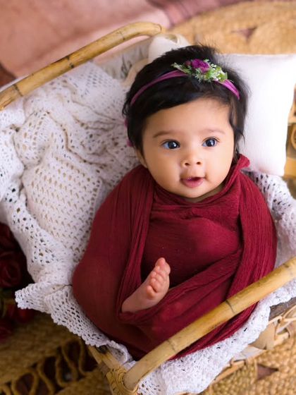 A precious three-month-old baby wrapped in red. Even after the newborn stage, we can still capture beautiful, cozy portraits like this one.