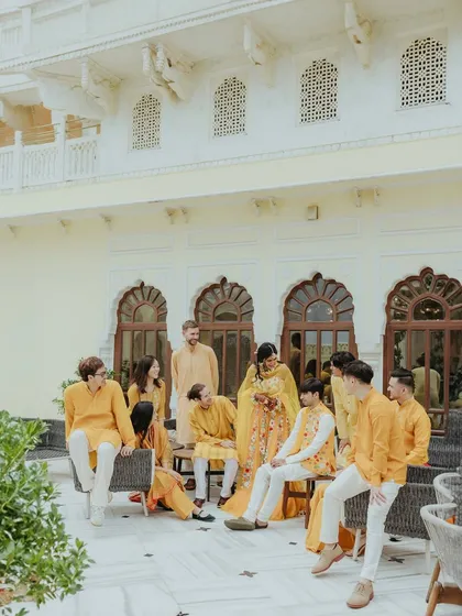A group portrait of the bride and groom with their entire bridal party, all coordinated in shades of yellow for the Haldi ceremony.