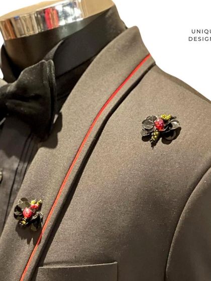 A close-up of a tuxedo lapel, featuring unique floral-inspired metal brooches. These small, custom details are what set our formal wear apart.