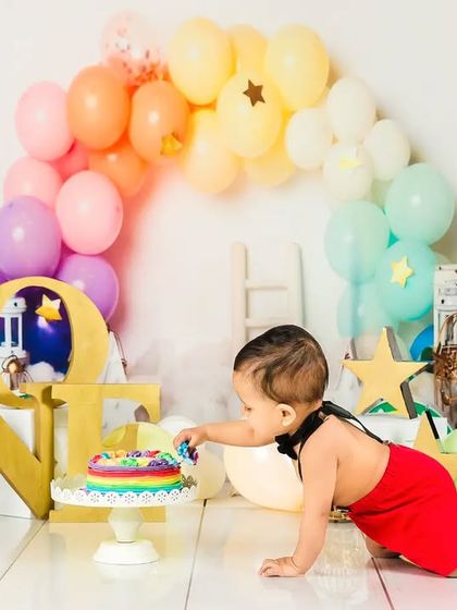 A baby boy crawls towards his rainbow cake, ready to make a mess and have some fun.