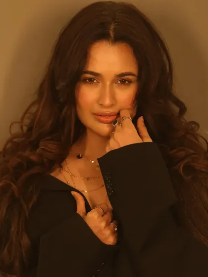 A close-up portrait that shows the detail of the soft waves and the warm, peachy tones used in her makeup.