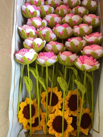 A box of mixed flower stems, including pink tulips and sunflowers, carefully packed for shipping.