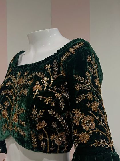 A classic combination of zardosi embroidery on a rich green velvet. This blouse features a wide neckline and full-length sleeves covered in intricate floral patterns.