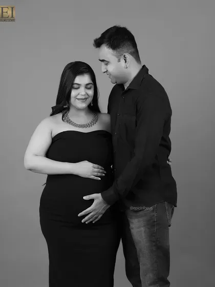 A tender black and white photo of a couple, with the husband's hand gently resting on the baby bump.