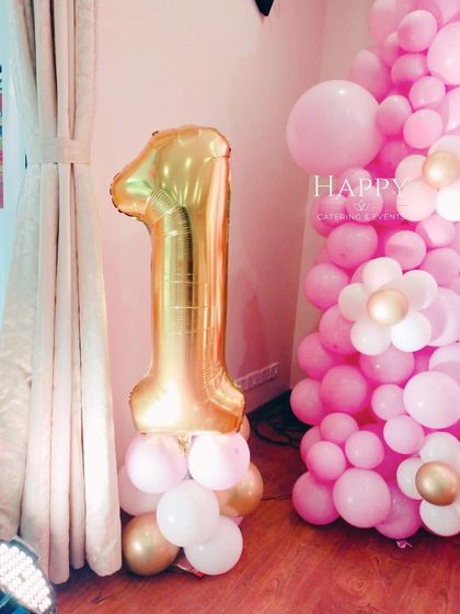 A large, gold foil number "1" balloon stands tall, marking a milestone first birthday. This simple but impactful decoration is a classic element for celebrating this special day.
