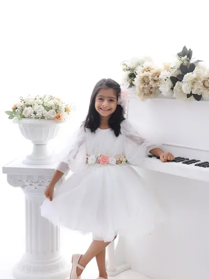 An elegant melody. This dreamy setup with a white piano and soft florals is perfect for older kids. It creates a sophisticated and timeless portrait that highlights your child's grace and personality.