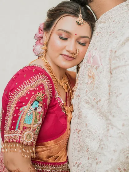 A close-up of the bride's serene expression as she rests on her groom. The focus is on the detailed artwork on her blouse sleeve and her flawless makeup.