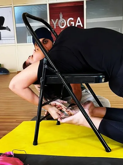 I am providing gentle assistance to a student in a chair-supported backbend. My hands-on guidance helps them to relax into the pose and get the maximum benefit from the stretch.