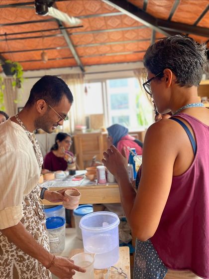 A candid moment of conversation and learning during a glazing session, where students get to see their pieces come to life with color.