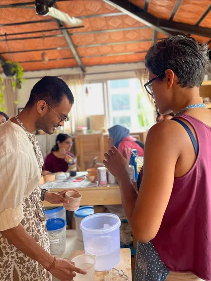 A candid moment of conversation and learning during a glazing session, where students get to see their pieces come to life with color.