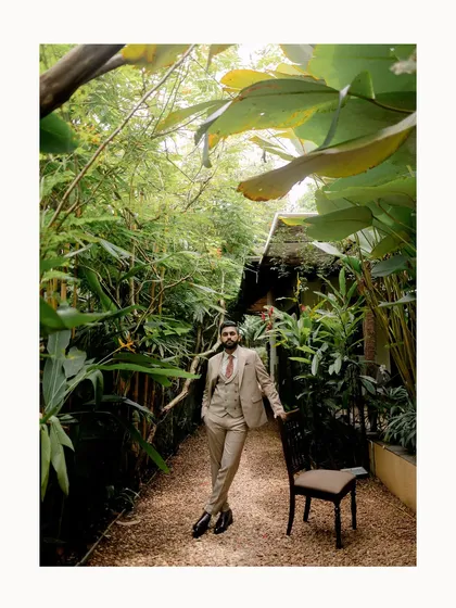 A groom in a stylish three-piece suit, posing confidently in a lush, tropical garden. This portrait captures his sharp style and relaxed demeanor on his wedding day.
