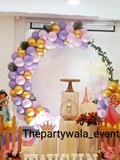 An elegant princess theme with a beautiful arch of pastel purple and gold balloons. The setup includes character cutouts and is perfect for a first birthday party.