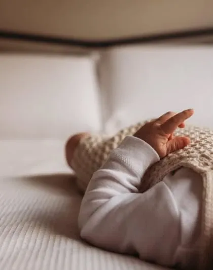 A detail shot focusing on a baby's hand on a soft blanket. This minimalist photo emphasizes the delicate and tiny nature of a newborn.