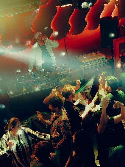 A dramatic shot of the dance floor at Tipsy Bull, with a disco ball and spotlight creating a classic party atmosphere.