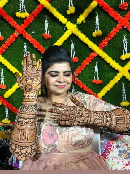 A happy bride posing against a colorful mehendi ceremony backdrop, showcasing her intricate henna.