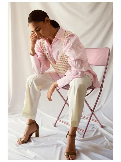 A full-length view of a creative styling concept. By layering a pearl bralette over a pink shirt and pairing it with simple white trousers and heels, I created a look that is both chic and unexpected.