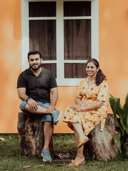 The couple posing on tree stumps, a rustic and natural setting for their pre-wedding shoot.