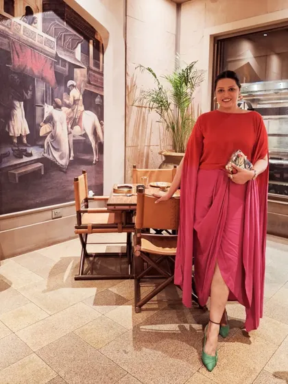 A color-blocked look with a red top and a pink draped skirt. The green shoes add an unexpected pop of color, showing that I love to play with bold combinations.