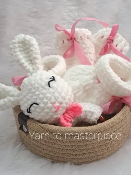 A close-up of the pink and white newborn gift hamper, showing the soft texture of the yarn and the cute bunny rattle, all ready for gifting.