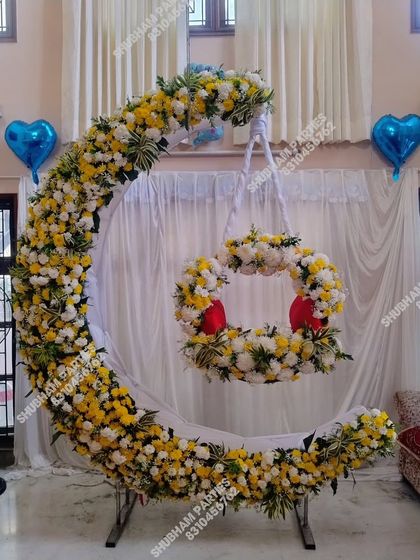 An exquisite moon-shaped cradle stand decorated with fresh yellow and white flowers for a naming ceremony.