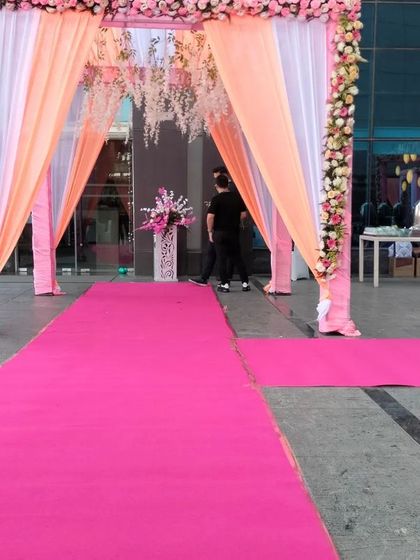 A long pink carpet leading to the main entrance arch, creating a grand walkway for guests arriving at the venue.
