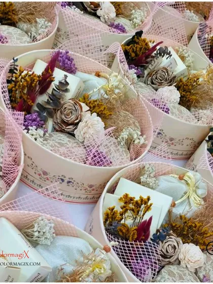 A collection of our customized wedding giveaways. These round boxes are filled with treats and adorned with delicate dried flower arrangements, creating a subtle and elegant gift.
