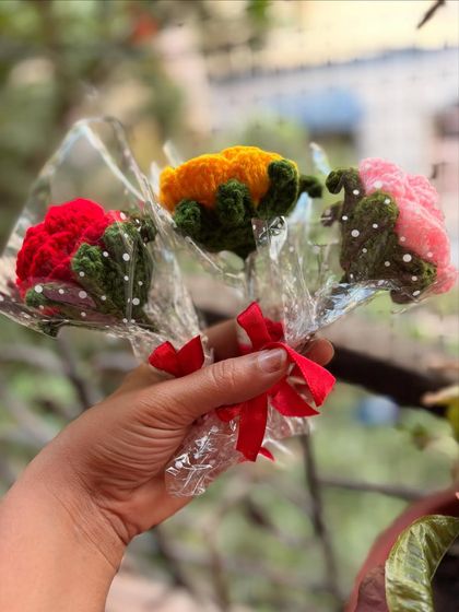 Holding a small bundle of three individually wrapped roses. This is a great option for gifting to a group of friends or colleagues.