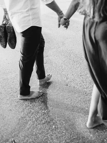 A detail-oriented shot focusing on the couple's feet in the sand and the groom carrying his shoes. It’s a small moment that tells a larger story of a relaxed day at the beach.