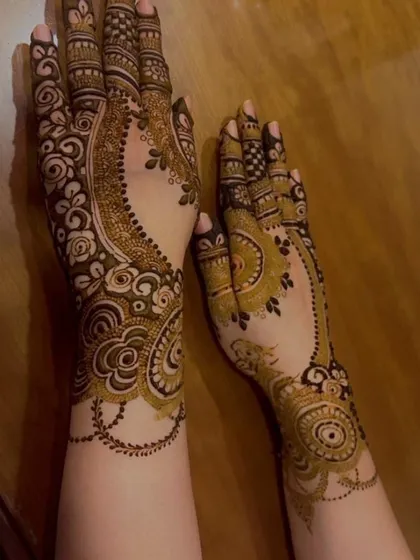 This design shows two different modern styles. One hand has a flowing Arabic vine pattern, while the other features a more contained mandala-style design on the back of the hand.