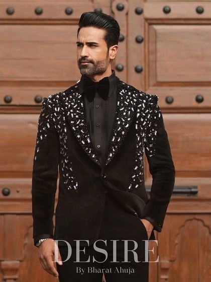 A full-length shot of the black velvet tuxedo against a grand wooden door. The look is one of pure, undeniable sophistication and power.